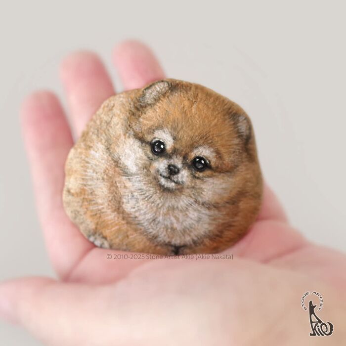 Painted stone of a cute dog held in hand by Japanese artist