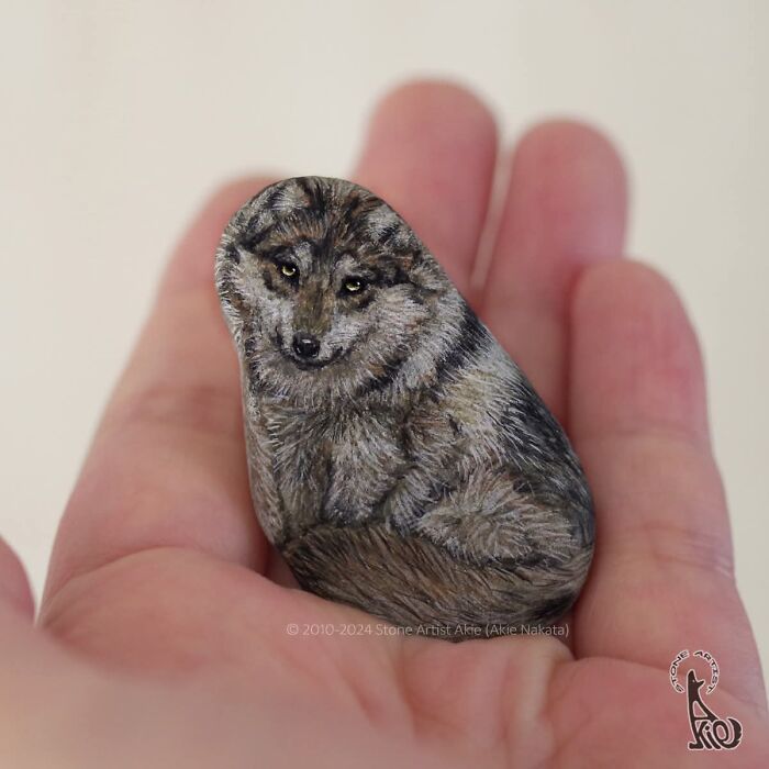 Japanese artist's detailed painted stone of a dog in hand