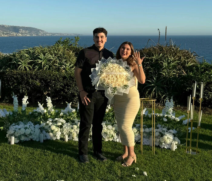 Happy couple posing with engagement ring and flowers after Laguna Beach proposal