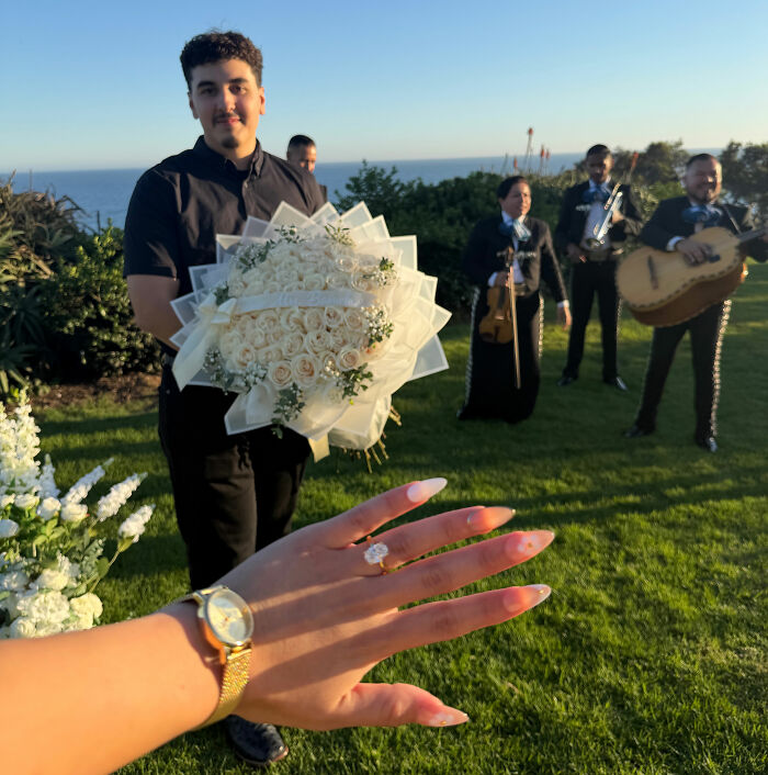 A newly engaged woman showing her ring in front of her fianc&eacute; and a mariachi band in Laguna Beach