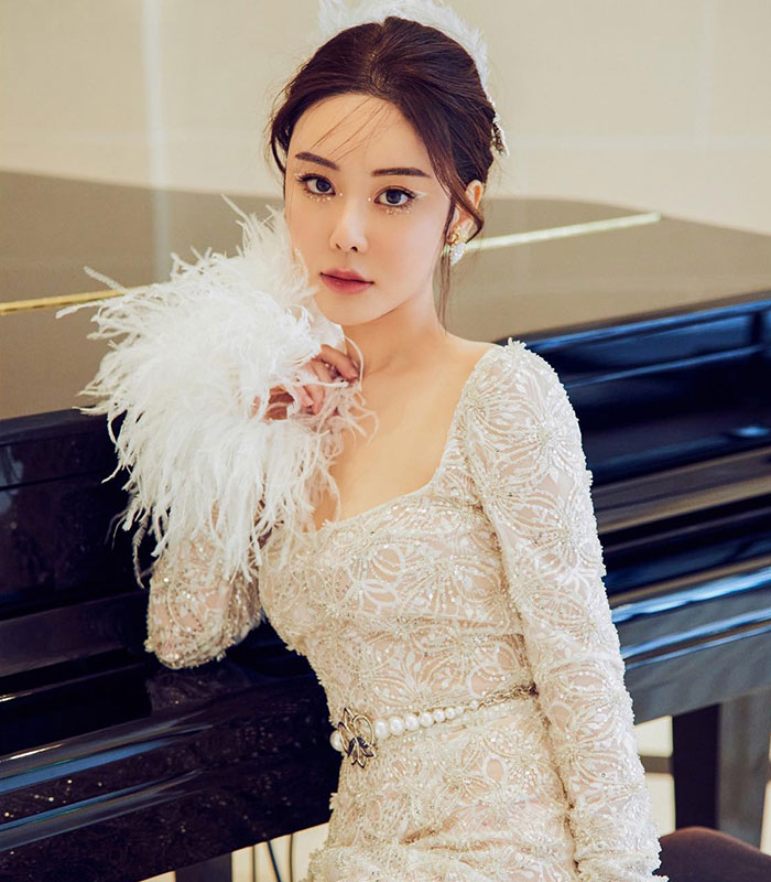 Elegant woman in white feathered gown sitting by black piano Elegant woman in white feathered gown sitting by black piano