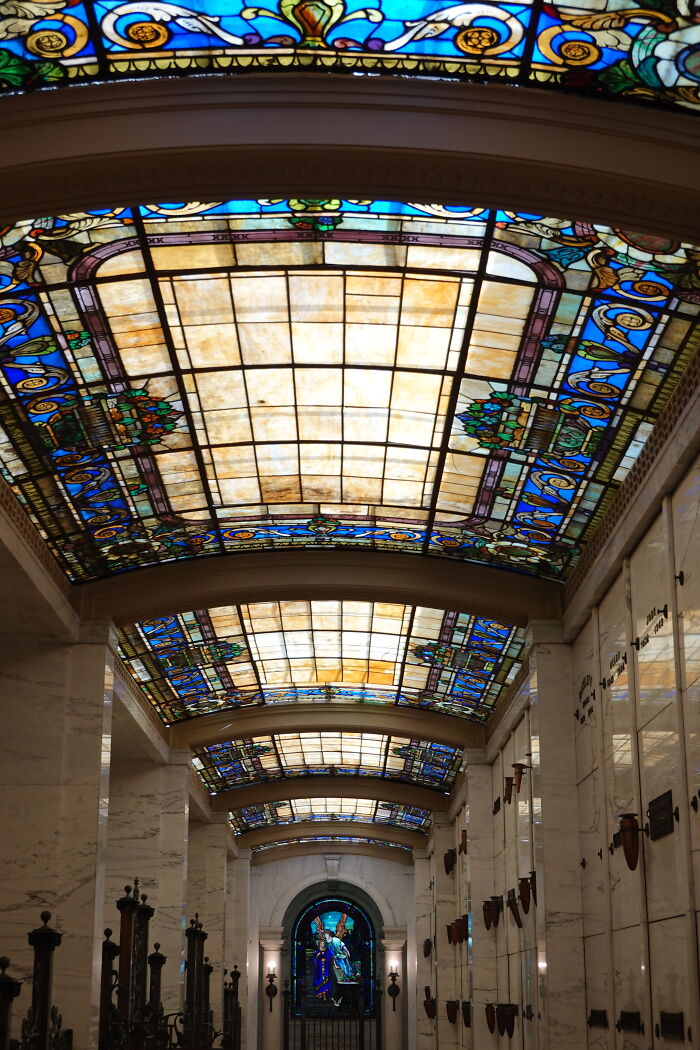 Corridor with stained-glass ceilings and a large colorful window at the end Corridor with stained-glass ceilings and a large colorful window at the end