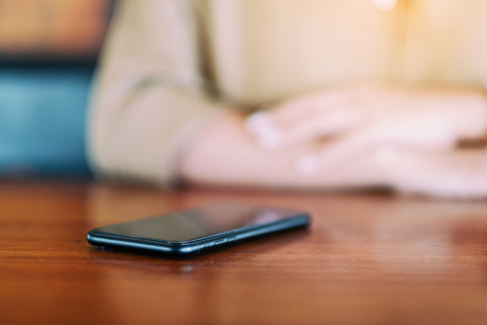 Smartphone on table with blurred person in background showing phone tracking context Smartphone on table with blurred person in background showing phone tracking context
