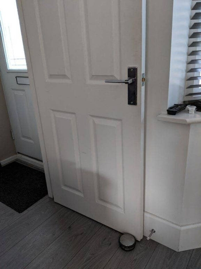 An improperly installed white door that cannot open fully because of a wall, showing a complete fiasco.