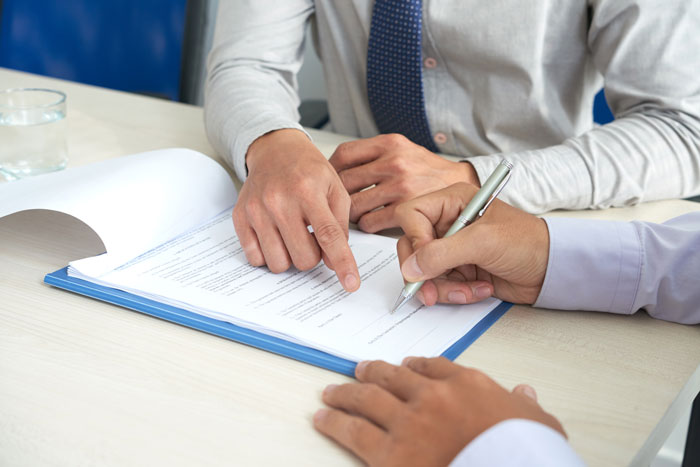 A person signing divorce documents during a difficult marriage separation