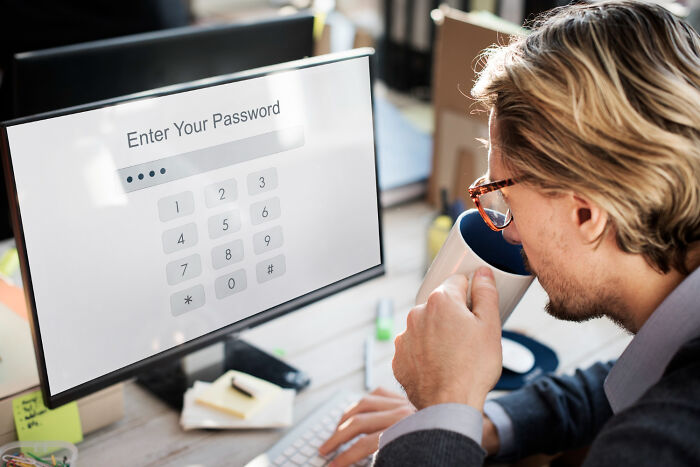 A man looking at a computer monitor screen, reflecting digital privacy issues in divorce stories.