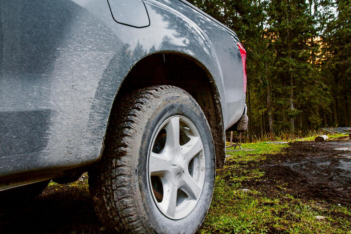 A dirty pickup truck tire on a grassy path, illustrating a moment that made partners question their intelligence.