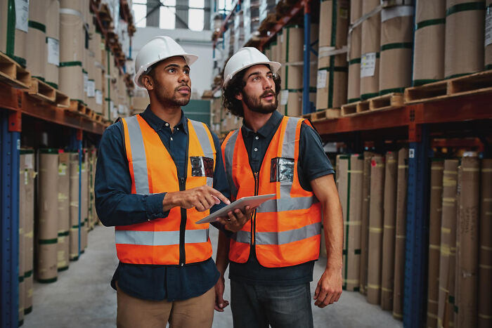 Two warehouse workers holding a tablet, relevant to obvious lies stories.