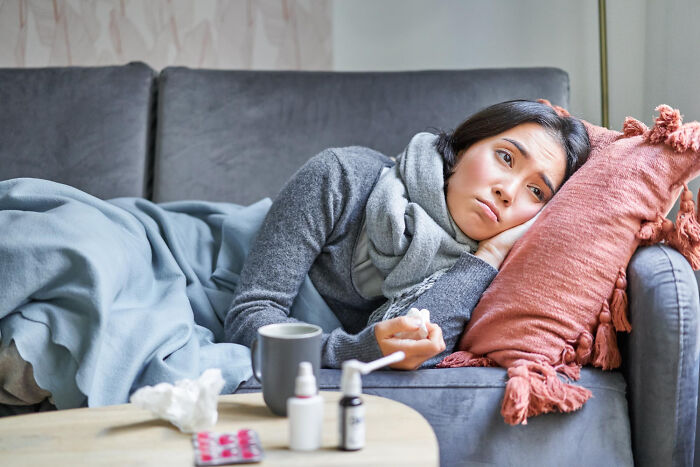 A sick woman lying on a sofa surrounded by medication, illustrating isolation in lesser-known cults.