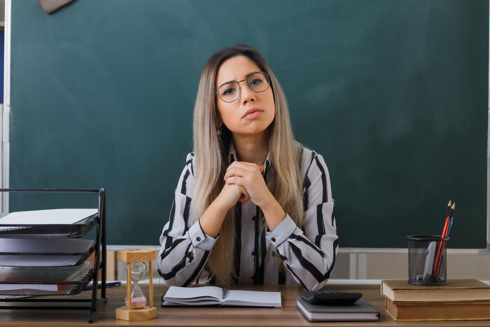 Serious teacher staring with disapproval in front of a chalkboard