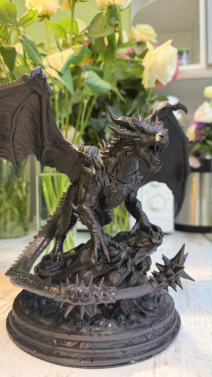 A detailed black dragon figure showcase of creative 3D prints on a table