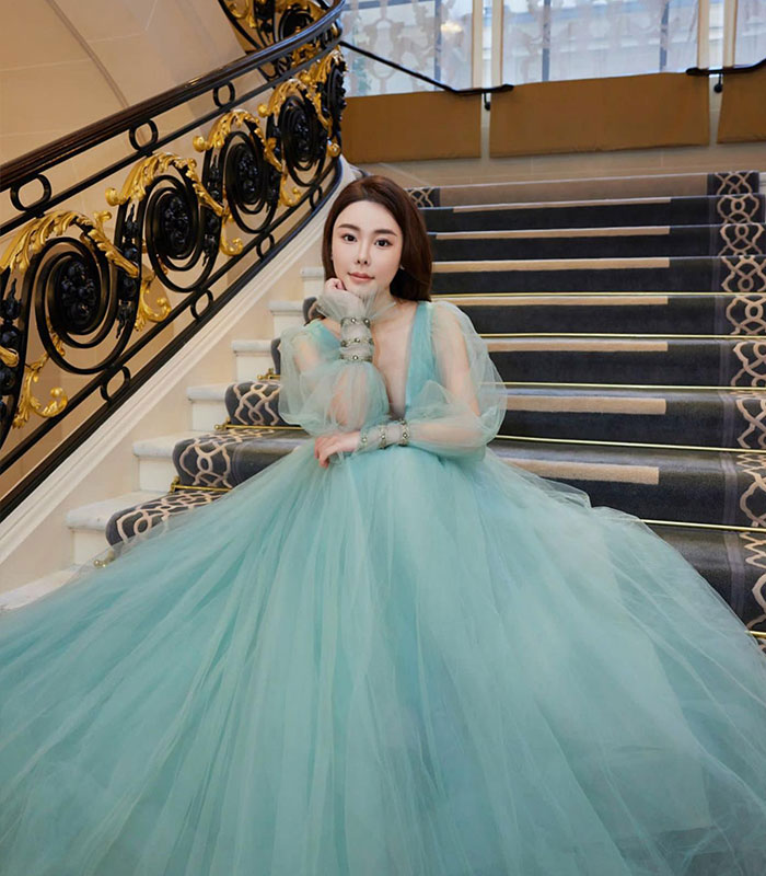Model in flowing blue gown sitting on grand staircase indoors Model in flowing blue gown sitting on grand staircase indoors