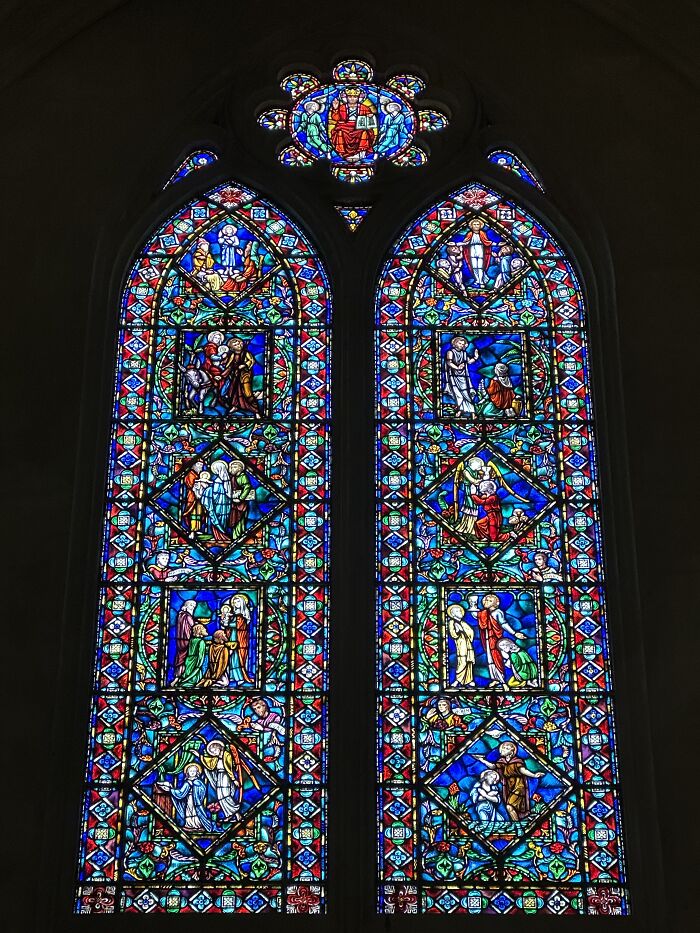 Two tall stained-glass windows with biblical scenes and colorful ornate borders Two tall stained-glass windows with biblical scenes and colorful ornate borders