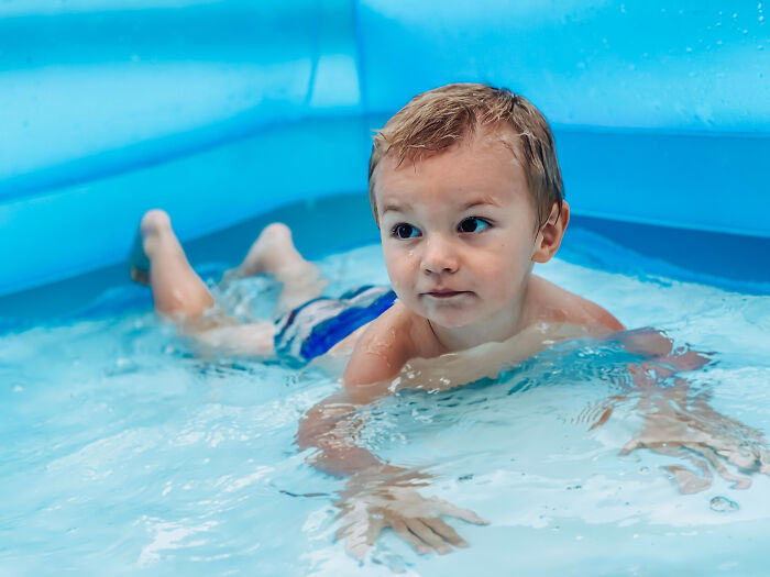 A little boy splashing happily inside an inflatable pool