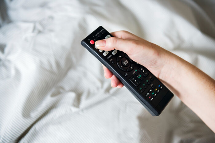 A hand holding a TV remote, symbolizing quiet isolation in real-life divorce stories.