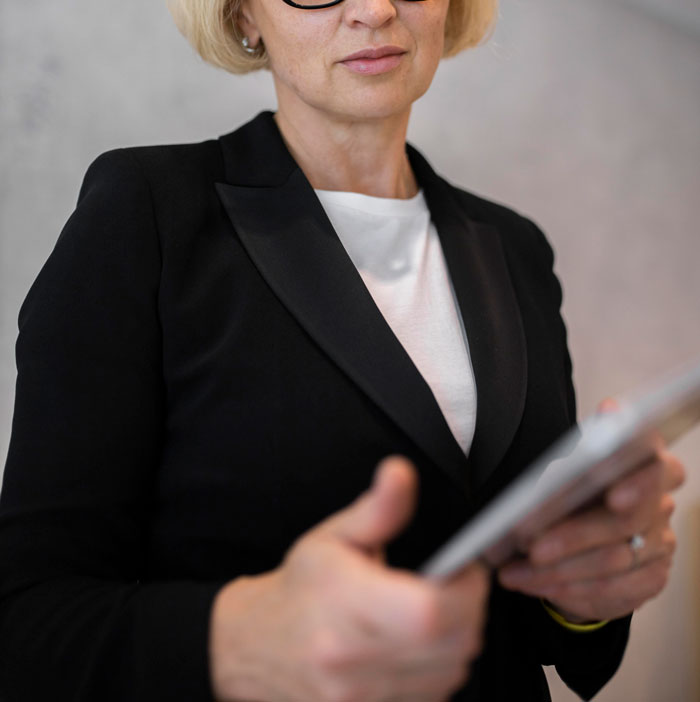 A woman wearing a black blazer and glasses holding a tablet after a marriage ends