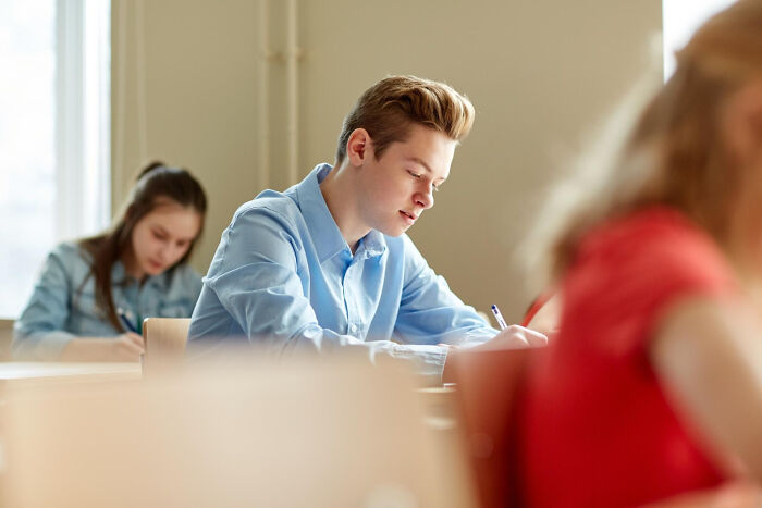 A teenage student taking an exam in class, showing the stress caused by infuriating teachers