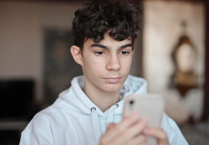 A young man looking seriously at his phone screen, facing tough breaking point moments