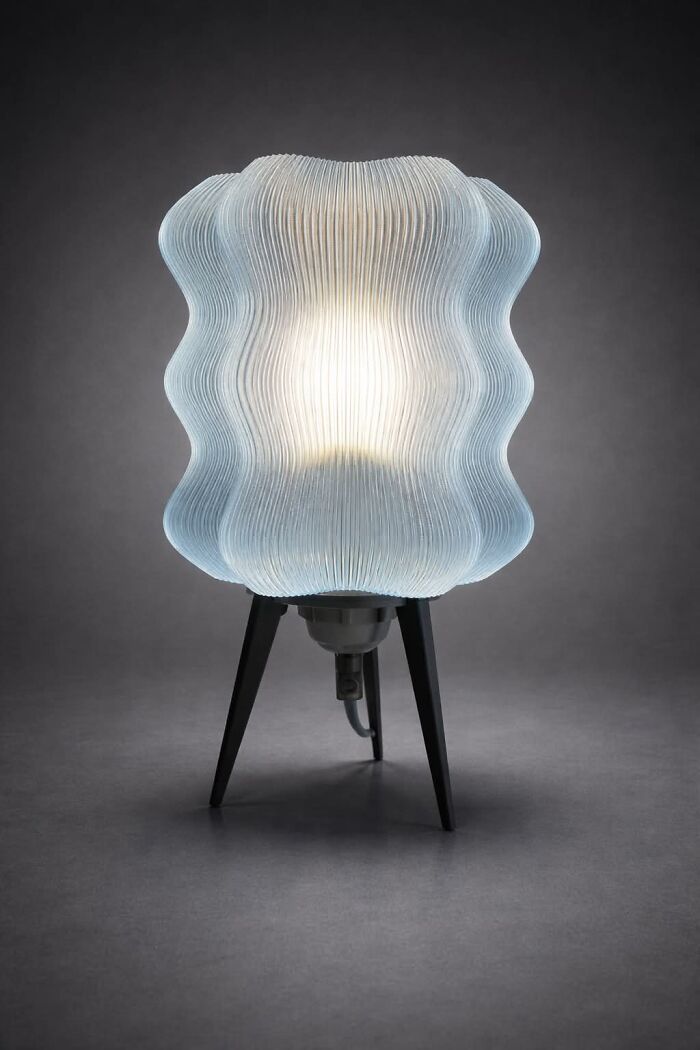 A glowing blue wavy lamp made using 3D prints on a dark background