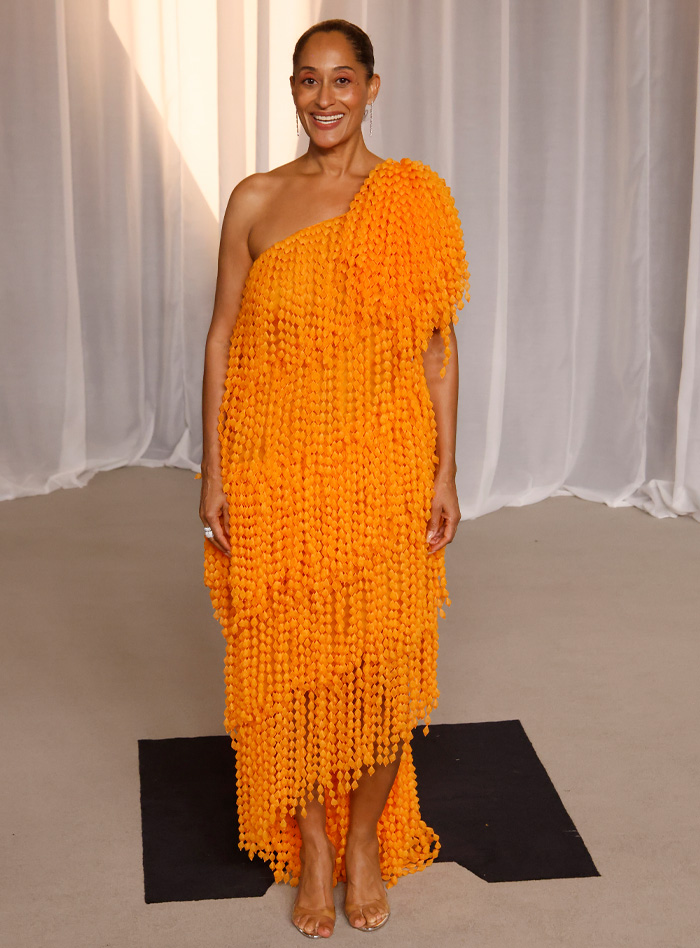 Woman in one-shoulder orange dress at Academy Museum Gala