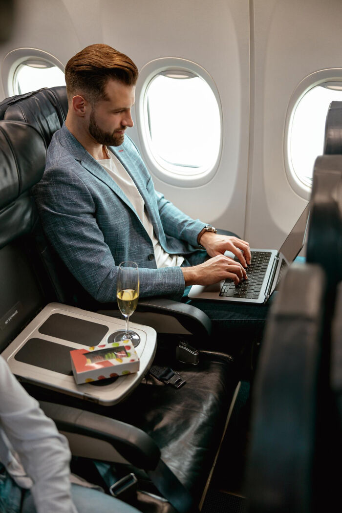 Man working on a laptop in first class trying to get better seats on flights