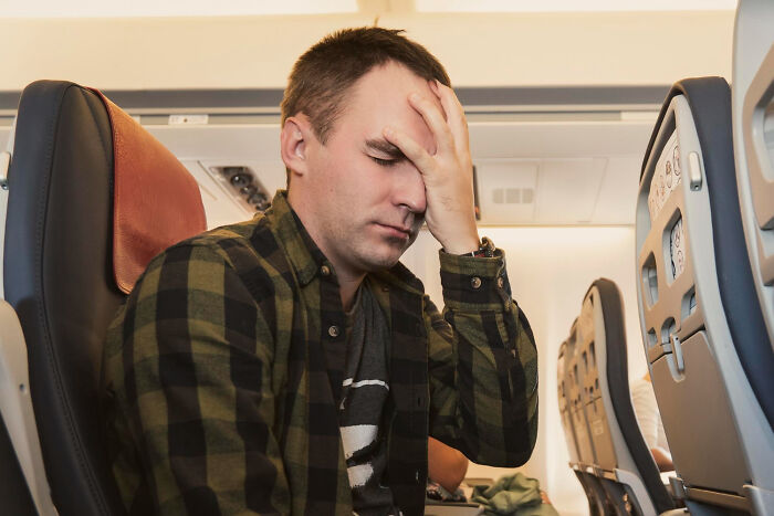 Stressed male passenger sitting in tight cabin seats on commercial flights