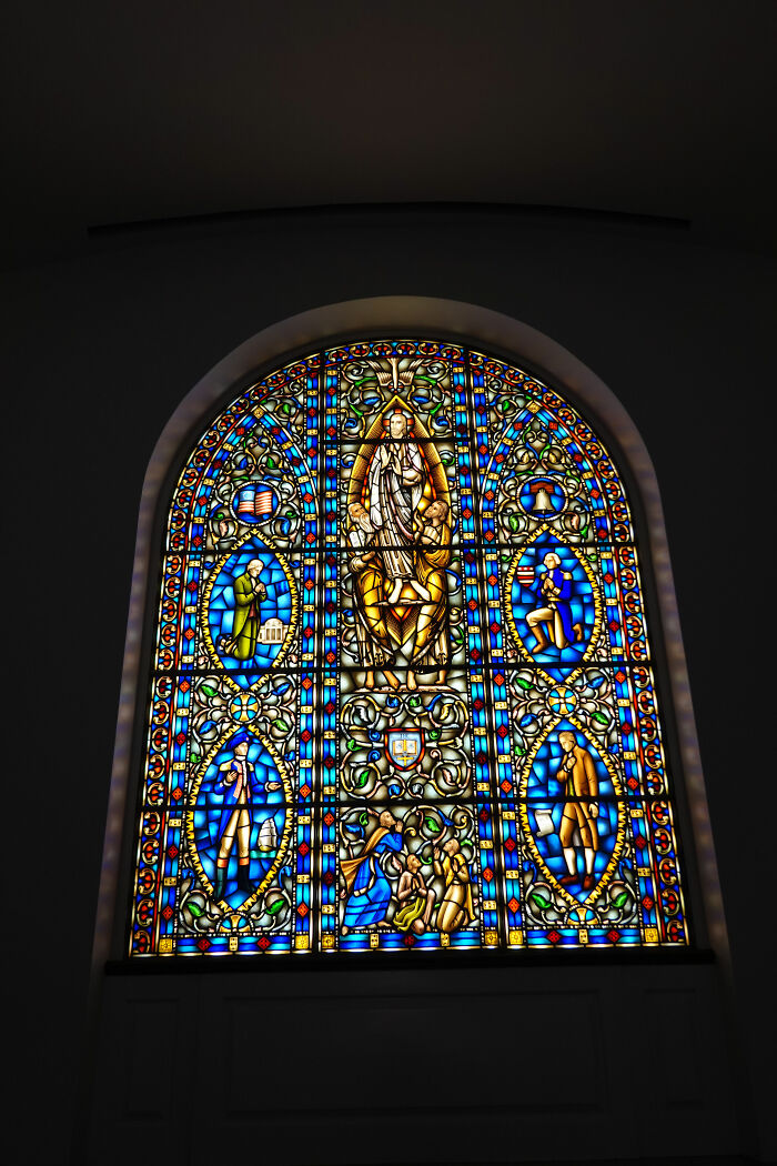 Colorful stained glass window featuring religious scenes in blue and gold hues Colorful stained glass window featuring religious scenes in blue and gold hues