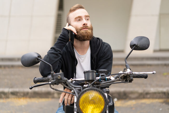 Man on motorcycle using phone with focused expression