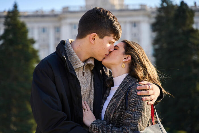 Young couple sharing a kiss outdoors in front of building