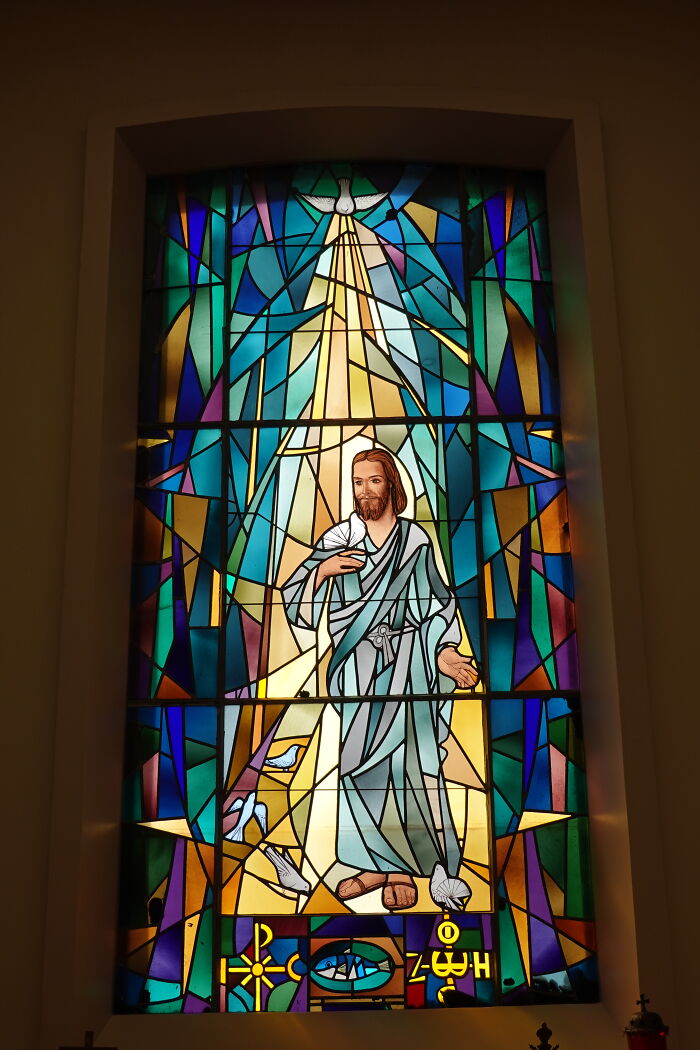 Bright stained glass window depicting Jesus with a dove and symbolic patterns Bright stained glass window depicting Jesus with a dove and symbolic patterns