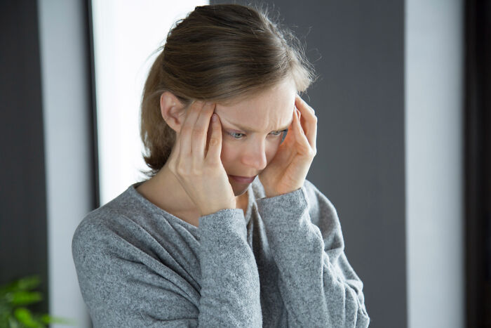 Woman holding her head in pain, representing stress management and health emergency tips.