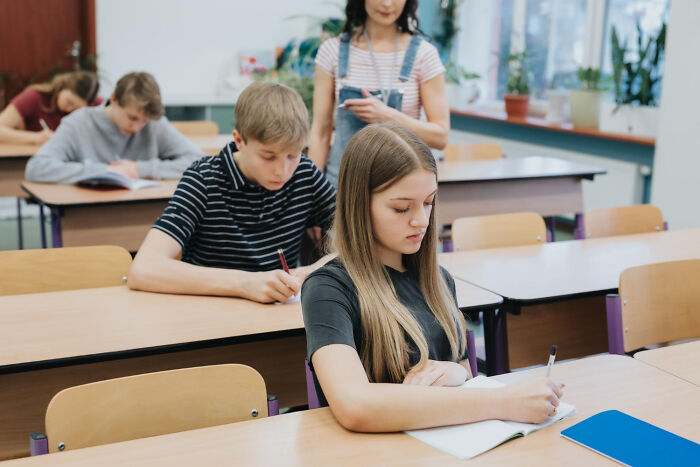 Frustrated students taking a test in a classroom with a strict teacher
