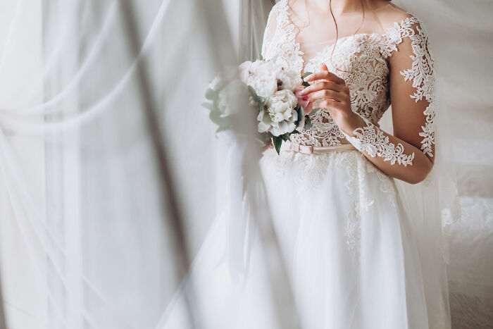 A bride wearing an elegant white lace wedding dress holding a flower bouquet, symbolizing love in divorce stories.