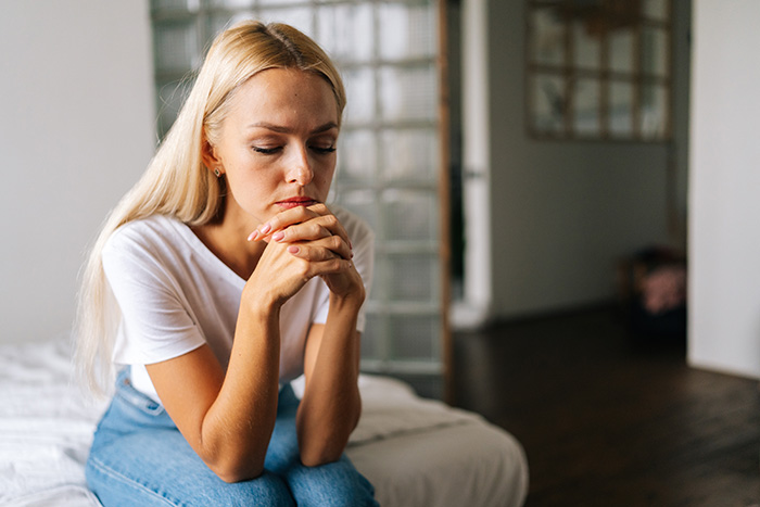 Thoughtful woman sitting alone indoors, reflecting after a girls trip that took an unexpected turn