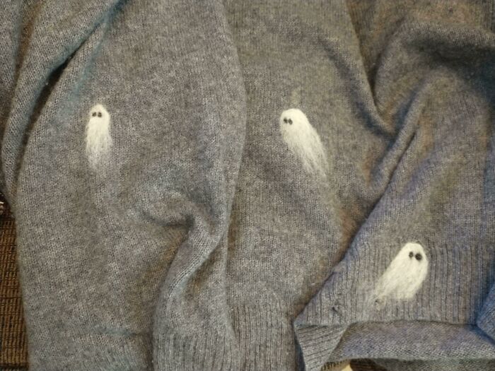 Cute needle-felted ghosts embroidered on a grey sweater, proving creativity can save money.