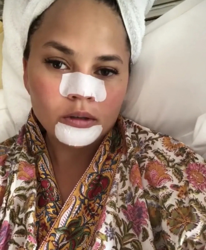 Woman in a robe wearing skincare pore strips on her nose and chin Woman in a robe wearing skincare pore strips on her nose and chin