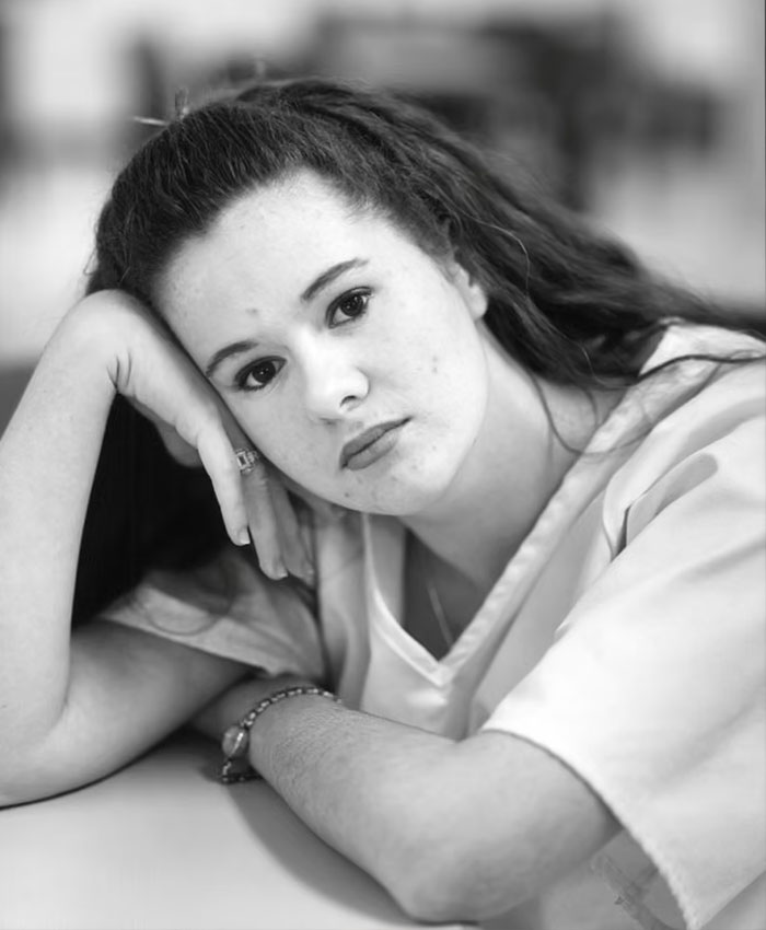 Black and white portrait of Christa Pike resting her head on her hand.