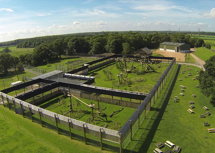 An aerial view of a large, secure tiger enclosure surrounded by green fields.