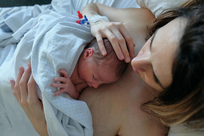 Newborn baby resting on mother's chest in hospital setting