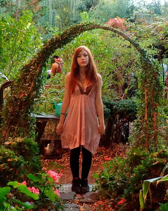 FIT student standing in garden archway surrounded by plants and flowers