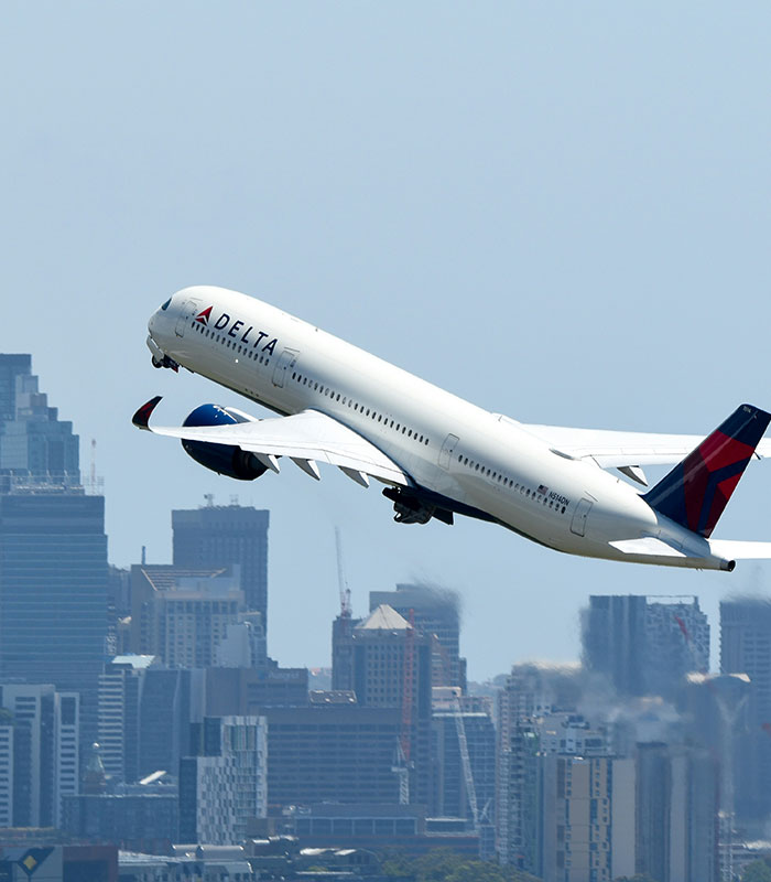 Delta airplane taking off against city skyline in clear blue sky Delta airplane taking off against city skyline in clear blue sky