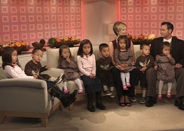 Jon Gosselin and Kate Gosselin seated on a couch surrounded by their children. Jon Gosselin and Kate Gosselin seated on a couch surrounded by their children.