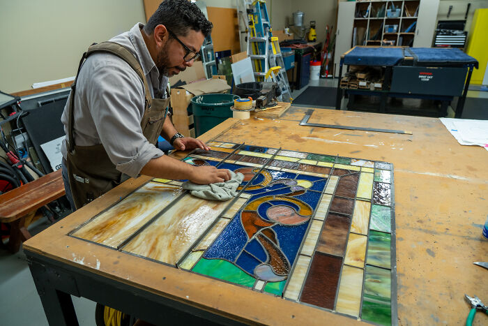 Expert cleaning a detailed stained-glass panel in workshop Expert cleaning a detailed stained-glass panel in workshop