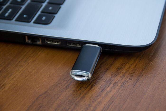 A USB flash drive plugged into a laptop showing questioning intelligence over technology