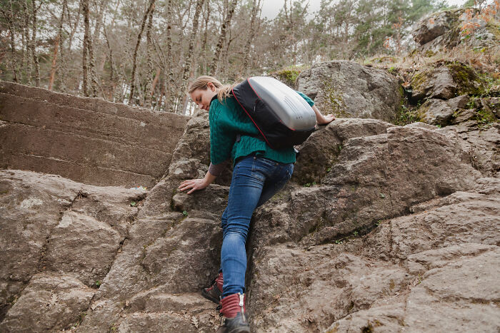 Woman climbing rocky mountain terrain with hiking gear and backpack