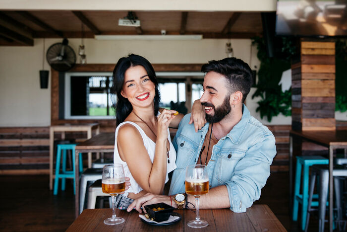 A happy young couple smiling at a bar, contrasting with sad real-life divorce stories