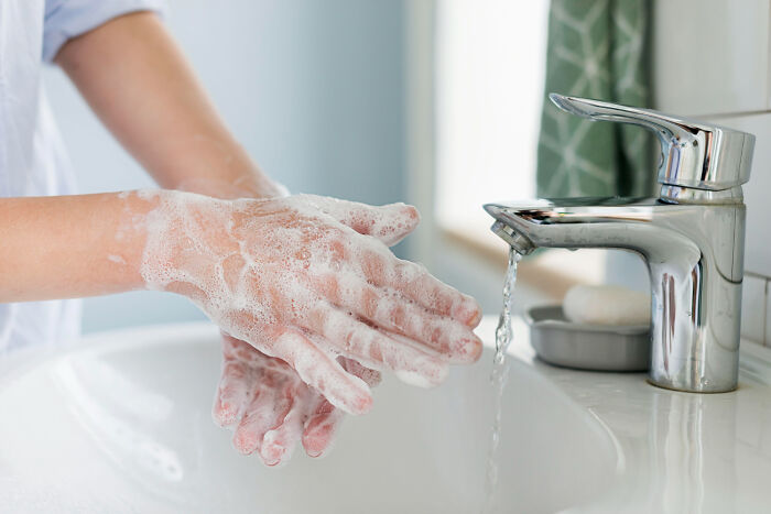 A healthcare worker washing hands thoroughly with soap, showing hygiene advice doctors and nurses give patients
