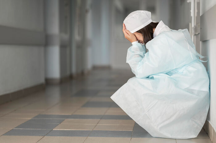 Tired healthcare workers sitting on the floor of a hospital hallway in distress