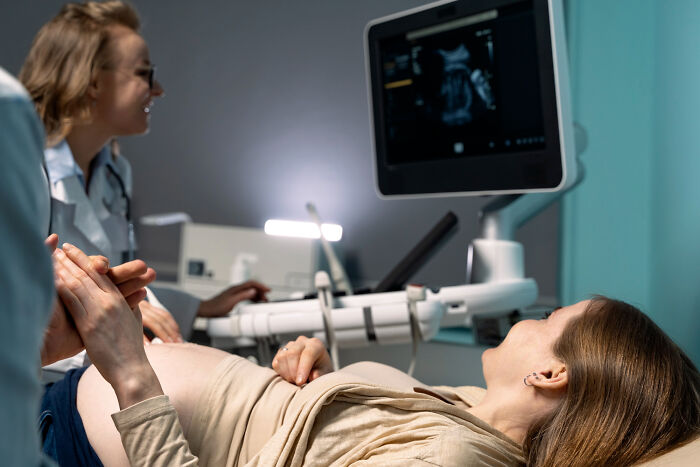 Pregnant woman having ultrasound with doctor in medical examination room