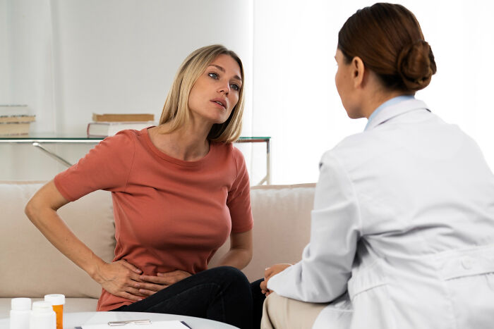 Woman explaining stomach pain to doctor in consultation